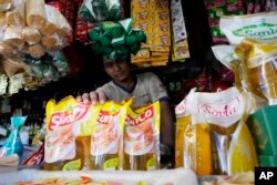 Seorang pedagang menunjukkan kemasan minyak goreng di kiosnya di sebuah pasar di Jakarta, Minggu, 17 April 2022. (Foto: AP)