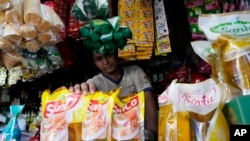 Seorang pedagang menunjukkan bungkusan minyak goreng di kiosnya di sebuah pasar di Jakarta, Minggu, 17 April 2022. (Foto: AP)