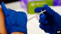 FILE - A health worker administers a dose of a Moderna COVID-19 vaccine during a vaccination clinic in Norristown, Pa., Dec. 7, 2021. Moderna vaccines are shipped at temperatures between minus 50-15 degrees Celsius and can be stored in the freezer at the same temperature.