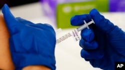 FILE - A health worker administers a dose of a Moderna COVID-19 vaccine during a vaccination clinic in Norristown, Pa., Dec. 7, 2021.