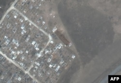 This satellite image released by Maxar Technologies April 22, 2022, shows a long trench freshly dug in a cemetery near Vynohradne, about 12 kilometers east of Mariupol, Ukraine, March 29, 2022.