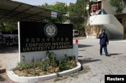 A security guard walks after a blast near a passenger van (not pictured) at the entrance of the Confucius Institute University of Karachi, Pakistan, April 26, 2022.