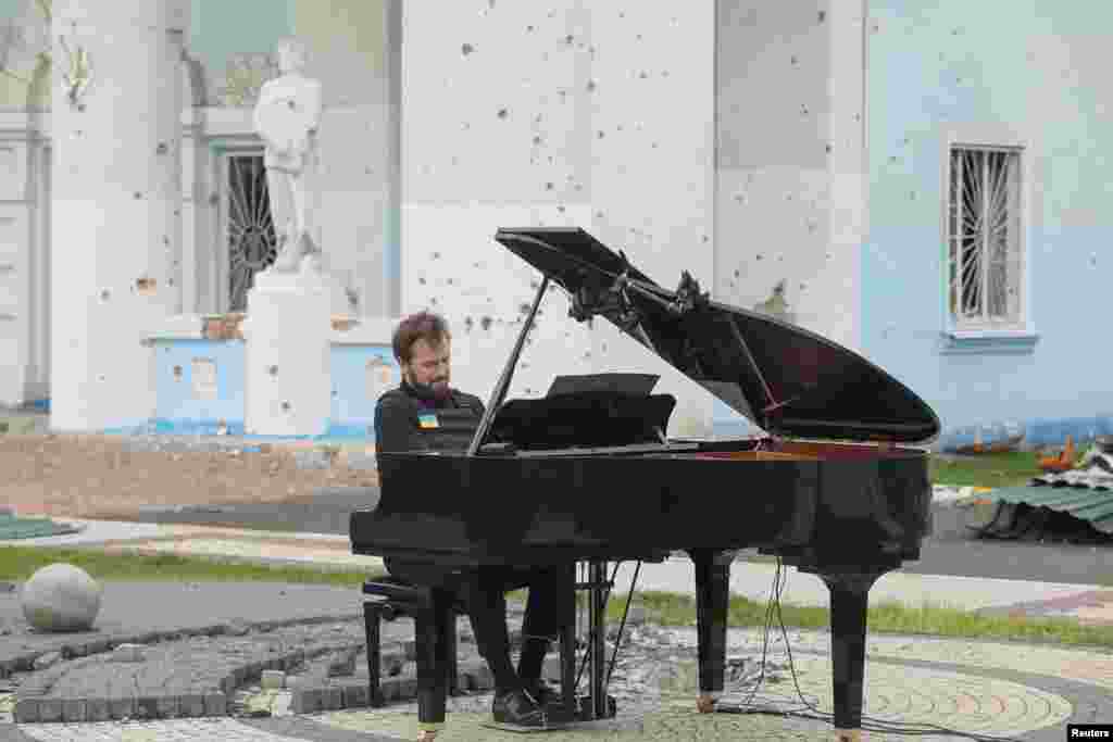 Lithuanian musician Darius Mazintas plays a piano in front of the Central House of Culture destroyed during Russia's invasion, in the town of Irpin, outside Kyiv, Ukraine, April 26, 2022.