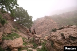 Two environmentalist brothers climb the Bamo mountain to find a spot for their camera traps, in the mission to protect the leopards, near Darbandikhan, Iraq, April 9, 2022. (REUTERS/Mohammed Jalal)