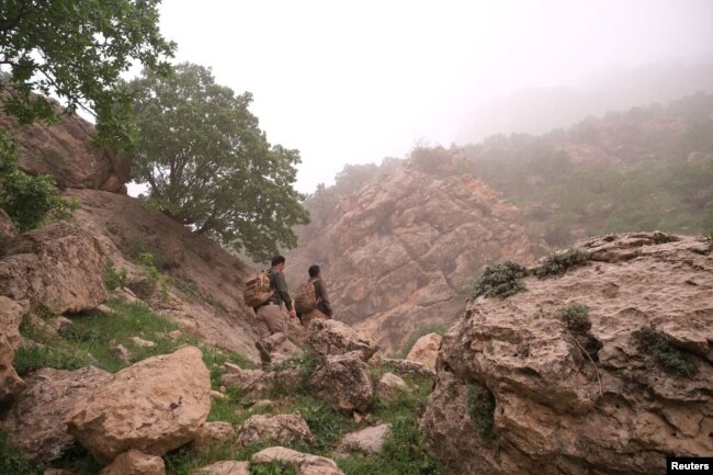 Two environmentalist brothers climb the Bamo mountain to find a spot for their camera traps, in the mission to protect the leopards, near Darbandikhan, Iraq, April 9, 2022. (REUTERS/Mohammed Jalal)