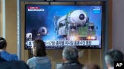 People watch a TV screen showing a news program reporting about North Korea's military parade with an image at a train station in Seoul, South Korea, Tuesday, April 26, 2022.