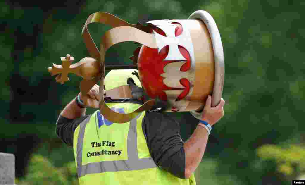 A worker carries a decorative crown before placing it on top of a flag pole ahead of planned celebrations for Queen Elizabeth&#39;s Platinum Jubilee, facing Buckingham Palace, in London, Britain.