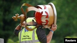 A worker carries a decorative crown before placing it on top of a flag pole ahead of planned celebrations for Queen Elizabeth&#39;s Platinum Jubilee, facing Buckingham Palace, in London, Britain.