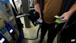 FILE - A customer prepares to pump gasoline into his car at a Sam's Club fuel island in Gulfport, Miss., Feb. 19, 2022. The U.S. economy shrank last quarter for the first time since the pandemic recession struck two years ago, the government reported April 28, 2022.