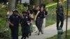 La policía evacua a las personas, incluida Sarah Cope corriendo con su perro, cerca de la escena de un tiroteo el viernes 22 de abril de 2022 en el noroeste de Washington, D.C.
