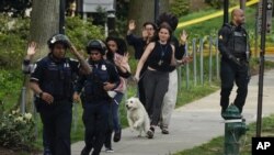 La policía evacua a las personas, incluida Sarah Cope corriendo con su perro, cerca de la escena de un tiroteo el viernes 22 de abril de 2022 en el noroeste de Washington, D.C.