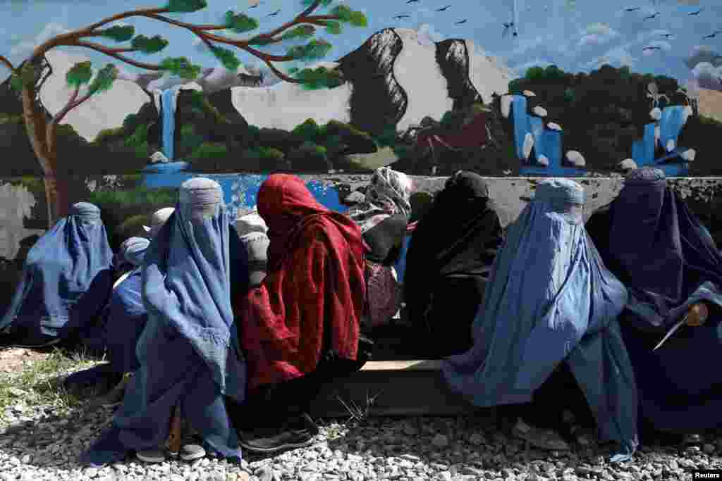Aghan women wait to receive food being given out by a Saudi Arabia humanitarian aid group at a distribution center in Kabul, April 25, 2022.