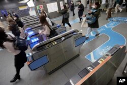 Penumpang melewati gerbang tiket di Stasiun Shibuya Tokyu Railways di Tokyo, Jepang, 20 April 2022. (AP/Eugene Hoshiko)