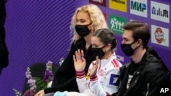 FILE - Russia's Kamila Valieva, center, reacts waiting for her results after performing in the women's short program during the ISU Grand Prix of Figure Skating Rostelecom Cup as her coach Eteri Tutberidze, left, sits next to her in Sochi, Russia, Nov. 26, 2021.