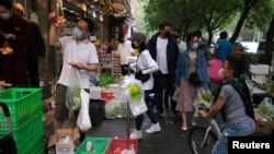 北京居民戴着口罩在街边市场购买蔬菜。北京市朝阳区日前发现病毒感染者后，居民担心也会出现上海那样的封城，纷纷购买储存食品。(2022年4月25日)