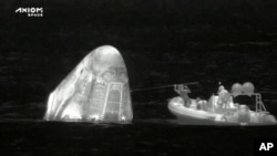 In this image from infrared video provided by SpaceX, recovery personnel approach the Dragon space capsule after splashdown in the Atlantic Ocean off the Florida coast on April 25, 2022.