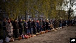 Worshipers stand next to their traditional cakes and painted eggs prepared for an Easter celebration during a religious service at a church in Bucha, on the outskirts of Kyiv, April 24, 2022.