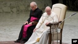 FILE - Pope Francis, with his hand on his right knee, is seen during his weekly general audience at the Vatican, March 2, 2022.