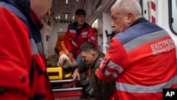 Ambulance workers help an injured Ukrainian serviceman to move to a hospital in Donetsk region, eastern Ukraine, April 23, 2022. 