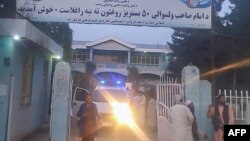 Taliban fighters and medical staff stand outside the gate of an hospital as they prepare to attend to the casualties after an explosion at Imam Sahib district in Kunduz province on April 22, 2022. 