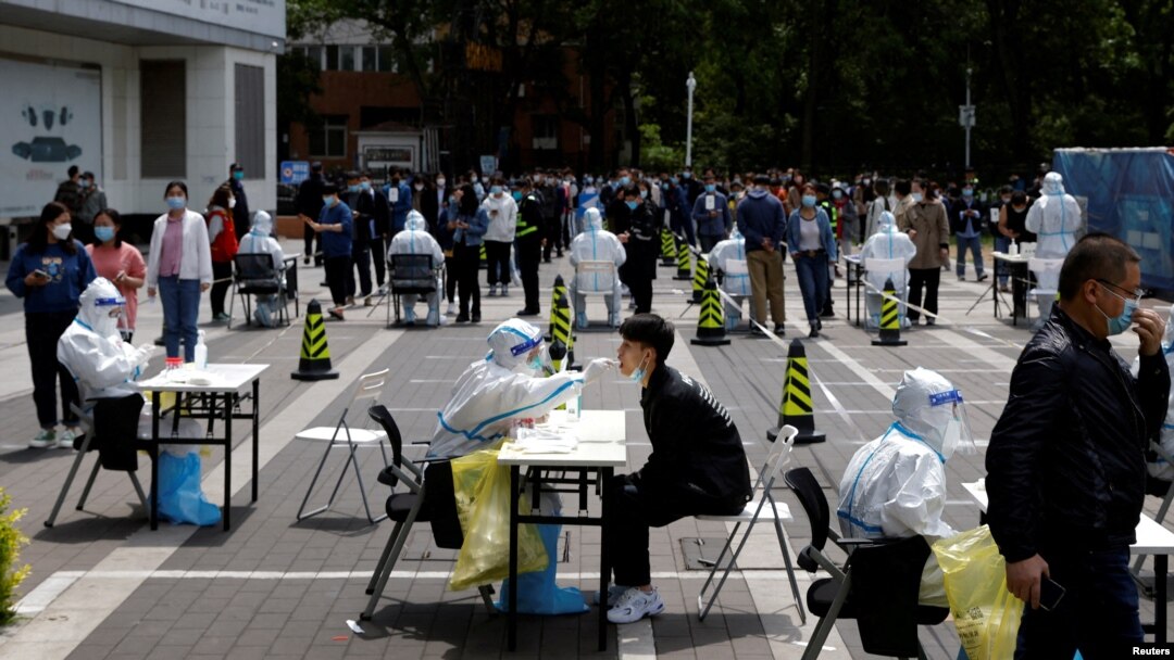 Seorang pekerja medis dengan pakaian pelindung mengumpulkan sampel swab dari seorang penduduk di tempat pengujian asam nukleat darurat di tengah wabah COVID-19 di Beijing, China. (Foto: Reuters)
