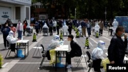 Seorang pekerja medis dengan pakaian pelindung mengumpulkan sampel swab dari seorang penduduk di tempat pengujian asam nukleat darurat di tengah wabah COVID-19 di Beijing, China. (Foto: Reuters)