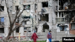 La gente camina cerca de un edificio residencial destruido durante el asalto de Rusia a Ucrania, en la ciudad portuaria de Mariúpol, en el sureste del país, el 22 de abril de 2022.