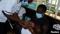 Pamela Omboko, a nurse administers a vaccine against Malaria for infants to Jeywellan Ochieng, 2, as she is held by her mother Julliet Achieng at the Yala Sub County Hospital Mother and Child Healthcare clinic in Gem, Siaya County, Kenya, Oct. 7, 2021.