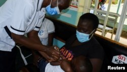 Pamela Omboko, une infirmière administre un vaccin contre le paludisme pour les nourrissons à Jeywellan Ochieng, 2 ans, en présence de sa mère Julliet Achieng à la clinique de santé pour mères et enfants de l'hôpital de Yala à Gem au Kenya, le 7 octobre 2021.