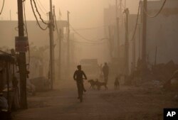 Seorang anak mengendarai sepeda di tengah asap tebal akibat kebakaran di TPA Bhalswa, New Delhi, India, Rabu, 27 April 2022. (AP/Manish Swarup)