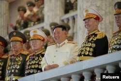 김정은(가운데) 북한 국무위원장이 지난 25일 평양 시내에서 열병식을 지켜보고 있다.