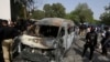 Pakistani investigators examine a burned van at the site of explosion in Karachi, April 26, 2022. 