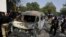 Pakistani investigators examine a burned van at the site of explosion in Karachi, April 26, 2022. 