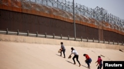 Migrantes que buscan asilo caminan cerca del muro fronterizo después de cruzar el río Bravo, en El Paso, Texas, EEUU, visto desde Ciudad Juárez, México, 6 de abril de 2022.