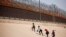 Migrantes que buscan asilo caminan cerca del muro fronterizo después de cruzar el río Bravo, en El Paso, Texas, EEUU, visto desde Ciudad Juárez, México, 6 de abril de 2022.