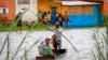 FILE - Family members take their belongings after their home was flooded during a week of heavy rain, in Antananarivo, Madagascar. Taken 1.24.2022