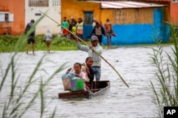 FILE - Family members take their belongings after their home was flooded during a week of heavy rain, in Antananarivo, Madagascar, Jan. 24, 2022. Extreme weather events across the continent linked to human-caused climate change are putting marine and terrestrial wildlife species at risk, according to biodiversity experts.