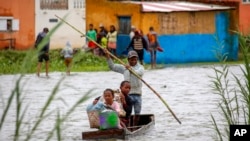 FILE - Family members take their belongings after their home was flooded during a week of heavy rain, in Antananarivo, Madagascar. Taken 1.24.2022