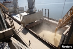 FILE - A dockyard worker watches as barley grain is mechanically poured into a ship at an agricultural exporter's shipment terminal in the southern Ukrainian city of Nikolaev, July 9, 2013.