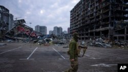 Një ushtarak kalon pranë një godine të shkatërruar nga bombardimet në Kiev, Ukrainë