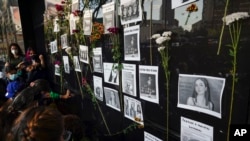 FILE - Flowers on the facade of the Attorney General's office surround images of Debanhi Escobar, right, and other missing women, during a protest in Mexico City, April 22, 2022.