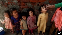 FILE - A health worker administers a polio vaccine to a child in Lahore, Pakistan, Feb. 28, 2022, as other children line up.