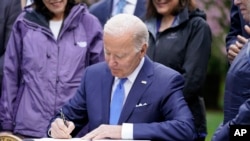 President Joe Biden signs an executive order intended to help restore national forests devastated by wildfires, drought and blight, during an event at Seward Park on Earth Day, April 22, 2022, in Seattle.