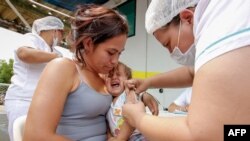 FILE - A Venezuelan woman and her baby are vaccinated against measles in Cucuta, Colombia, at the international brigde Simon Bolivar on the border with Venezuela, on March 21, 2018. 