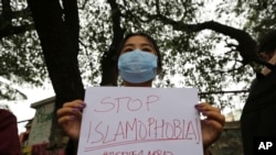 FILE- A woman holds a placard during a protest against the killing of a Muslim man last Sept. in Belagavi district of the southern Indian state of Karnataka, in Bengaluru, India, Oct. 5, 2021.