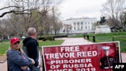 Paula and Joey Reed, orang tua dari Trevor Reed, berdiri di dekat spanduk yang bertuliskan "Bebaskan Trevor Reed" di Lafayette Square dekat Gedung Putih , di Washington, pada 30 Maret 2022. (Foto: AFP/Stefani Reynolds)