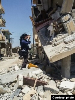 Spanish journalist Natalia Sancha takes photos of a destroyed building in the village of Qariatein in the Syrian desert in April 2016. (Photo courtesy: Natalia Sancha/Mohammed Miri)