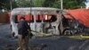 An officer adjusts crime scene tape at a blast site, a day after a suicide attack on a van near the Chinese-operated Confucius Institute at the University of Karachi, in Pakistan, April 27, 2022. 