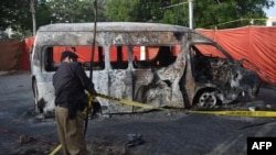 An officer adjusts crime scene tape at a blast site, a day after a suicide attack on a van near the Chinese-operated Confucius Institute at the University of Karachi, in Pakistan, April 27, 2022. 