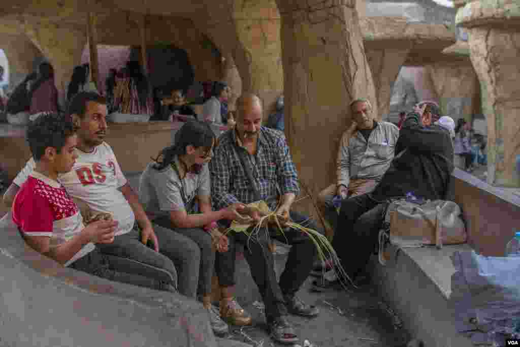 Sameh teaches his daughter, Mohrael, how to weave palm leaves inside the Church of Saint Samaan the Tanner, which permitted larger celebratory gatherings this Easter season, in Cairo, April 17, 2022. (Hamada Elrasam/VOA)